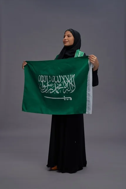 امرأة سعودية تحمل علم المملكة العربية السعودية في الاستوديو