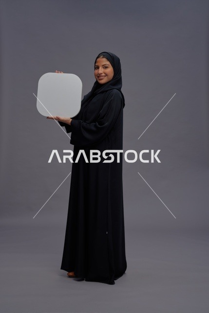 امرأة عربية بالعباءة تحمل لوحة فارغة في الاستوديو