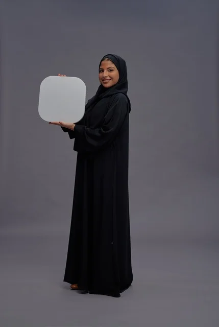 امرأة عربية بالعباءة تحمل لوحة فارغة في الاستوديو