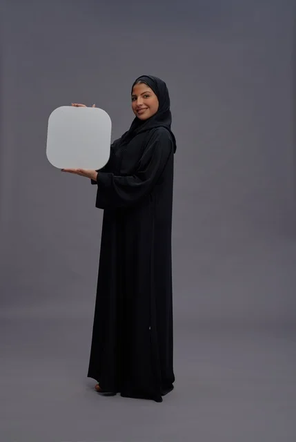 امرأة عربية بالعباءة السوداء تحمل لوحة بيضاء فارغة