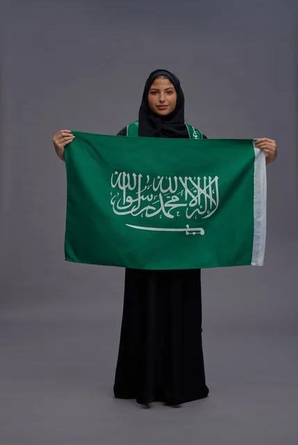 امرأة سعودية تحمل علم المملكة في الاستوديو