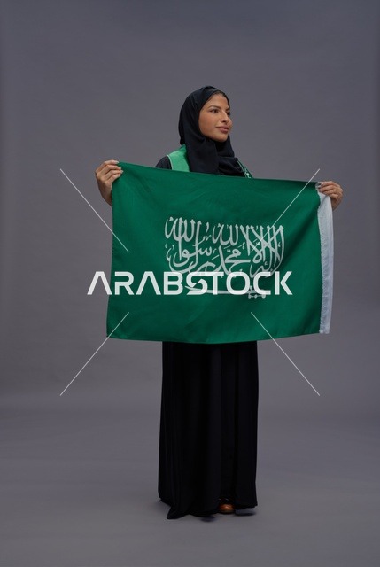 امرأة سعودية تمسك بعلم المملكة في استوديو