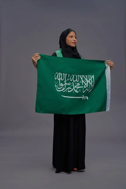 امرأة سعودية تمسك بعلم المملكة في استوديو
