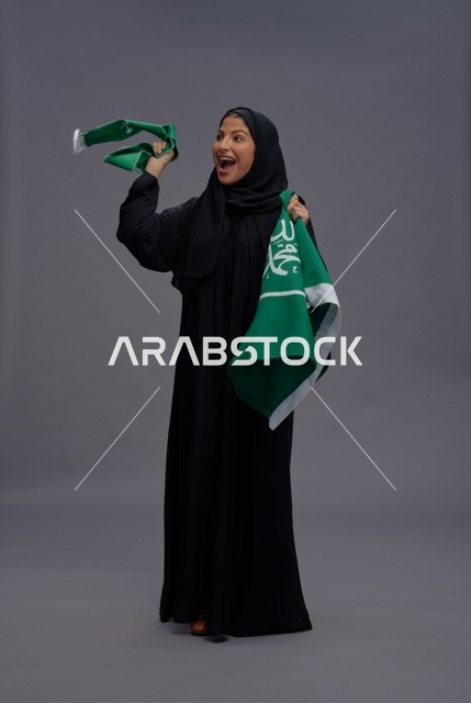 امرأة سعودية تحتفل وتحمل علم المملكة العربية السعودية