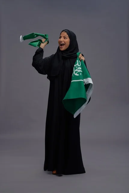 امرأة سعودية تحتفل وتحمل علم المملكة العربية السعودية