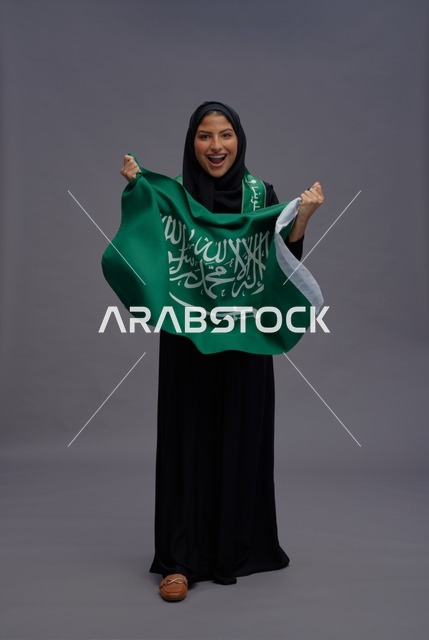 Saudi Woman Holding Kingdom Flag in Studio Setting