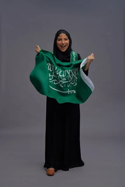 Saudi Woman Holding Kingdom Flag in Studio Setting