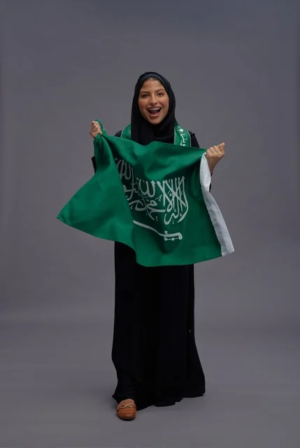 امرأة سعودية تمسك علم المملكة العربية السعودية