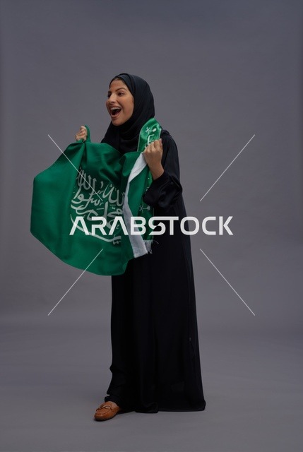 امرأة سعودية تحمل علم المملكة العربية السعودية باحتفال