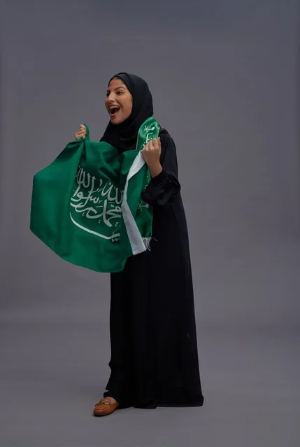امرأة سعودية تحمل علم المملكة العربية السعودية باحتفال