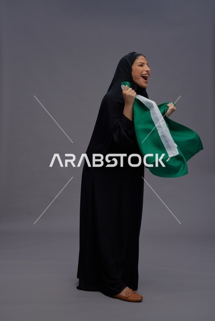 امرأة سعودية تحمل علم المملكة وتفخر بالاستوديو