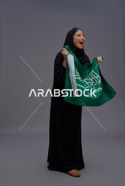 امرأة سعودية تمسك علم المملكة العربية السعودية بحماس