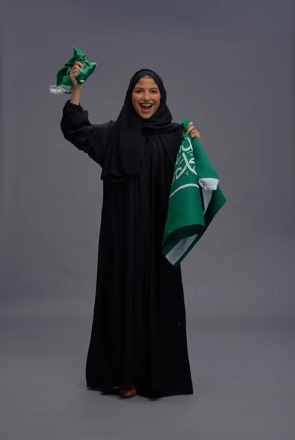 امرأة سعودية تمسك بعلم المملكة في الاستوديو