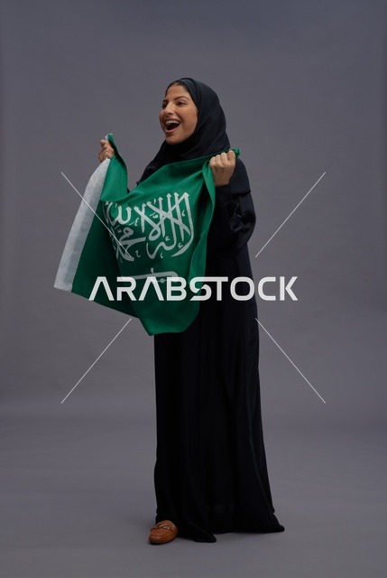 امرأة سعودية تمسك علم المملكة في استوديو تصوير