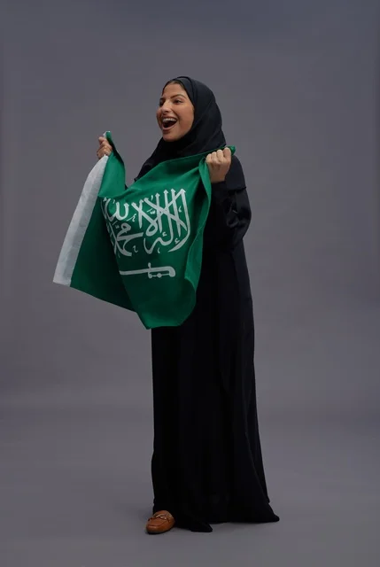 امرأة سعودية تمسك علم المملكة في استوديو تصوير