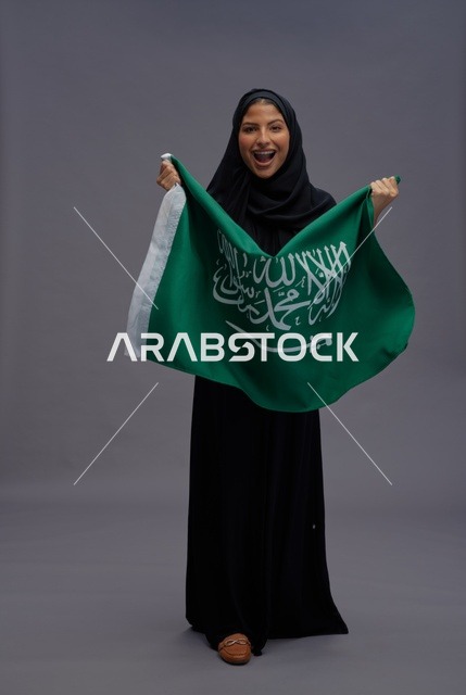 امرأة سعودية تحمل علم المملكة العربية السعودية في الاستوديو