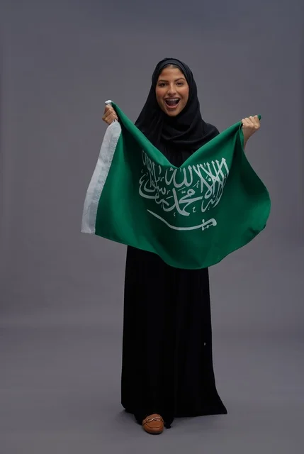 امرأة سعودية تحمل علم المملكة العربية السعودية في الاستوديو