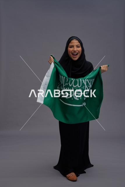 امرأة سعودية تحتفل بحمل علم المملكة العربية السعودية