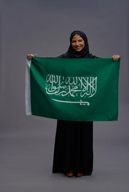 امرأة سعودية تمسك علم المملكة العربية السعودية