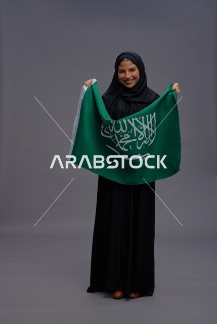 امرأة سعودية تمسك علم المملكة في الاستوديو