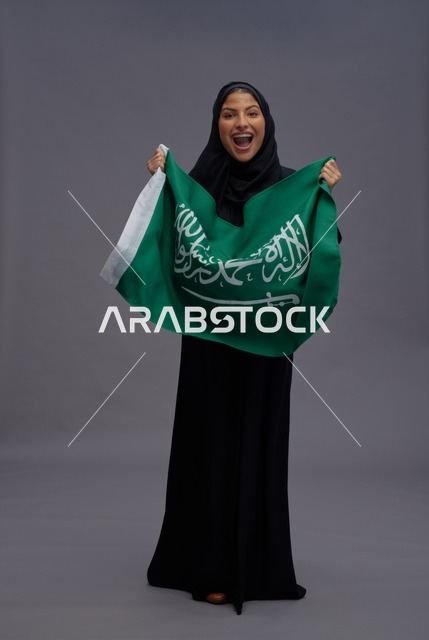 امرأة سعودية تمسك علم المملكة العربية السعودية