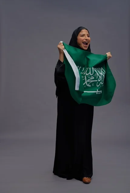 امرأة سعودية تحمل علم المملكة العربية السعودية
