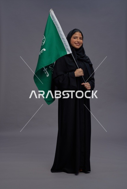 امرأة سعودية تحمل علم المملكة العربية السعودية باستوديو