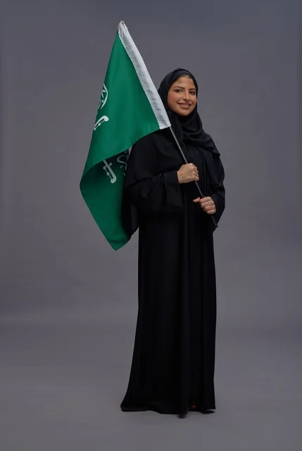 امرأة سعودية تحمل علم المملكة العربية السعودية باستوديو