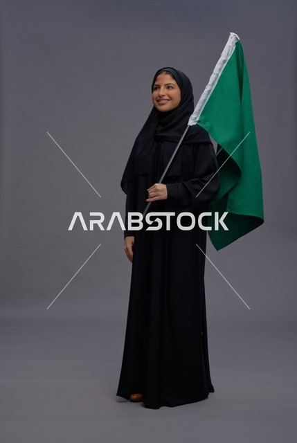 Saudi Woman Holding Saudi Flag in Studio Portrait