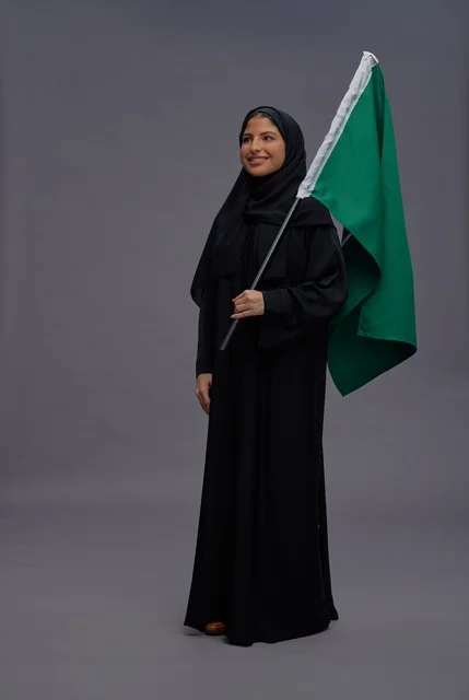 Saudi Woman Holding Saudi Flag in Studio Portrait