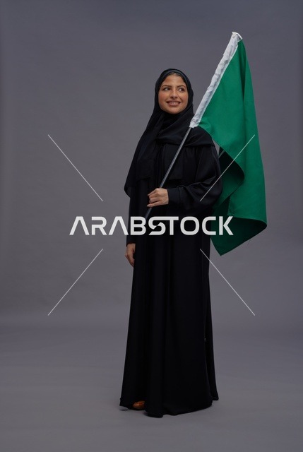 امرأة سعودية تمسك علم المملكة في الاستوديو