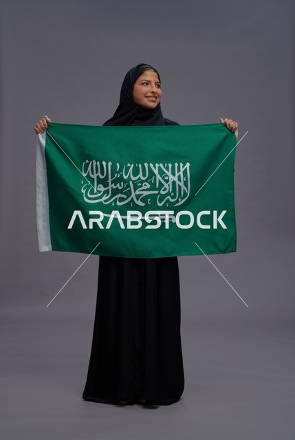 امرأة سعودية تمسك علم المملكة في استوديو
