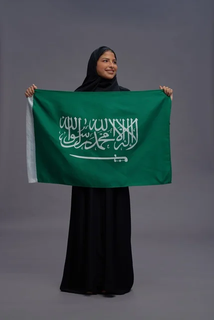 امرأة سعودية تمسك علم المملكة في استوديو