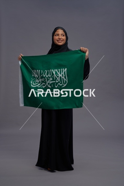 امرأة سعودية تحمل علم المملكة في الاستوديو