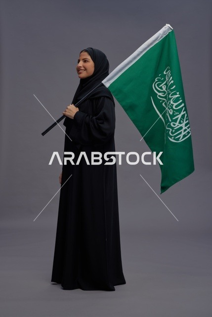 امرأة سعودية مع العلم الوطني في خلفية استوديو