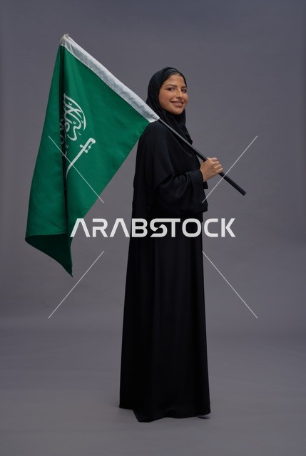امرأة سعودية تحمل علم المملكة في الاستوديو