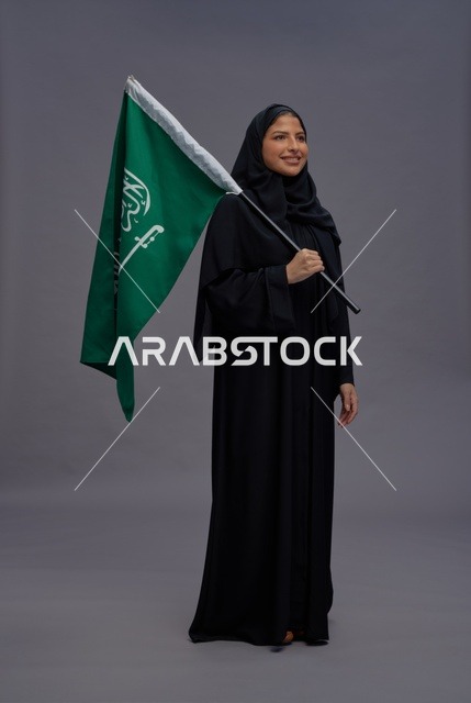 امرأة سعودية تحمل علم المملكة في الاستوديو
