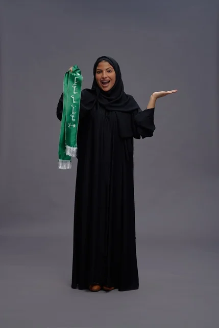 امرأة سعودية تحمل وشاح اليوم الوطني في الاستوديو
