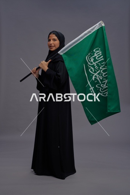 Saudi Woman in Abaya Holding National Flag in Studio