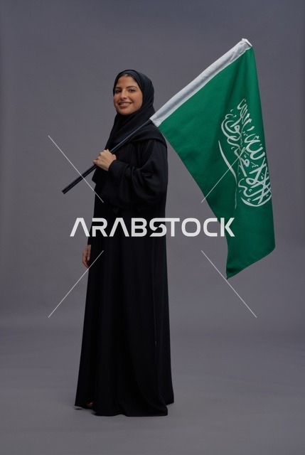 امرأة سعودية تمسك علم المملكة العربية السعودية في استوديو