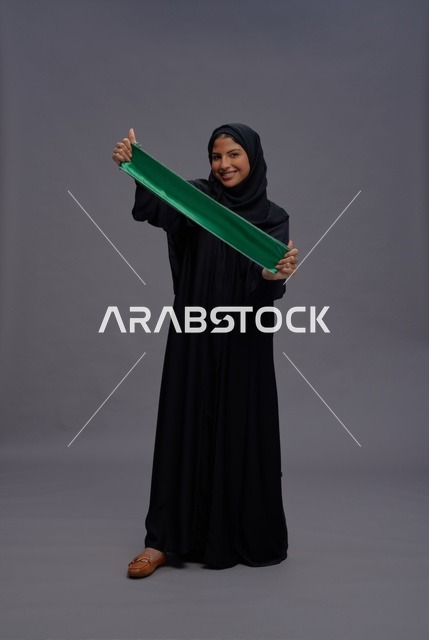 امرأة سعودية تحمل علم المملكة العربية السعودية في استوديو