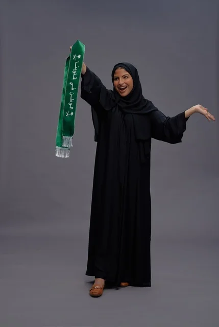 امرأة سعودية تمسك بوشاح الوطن في استوديو
