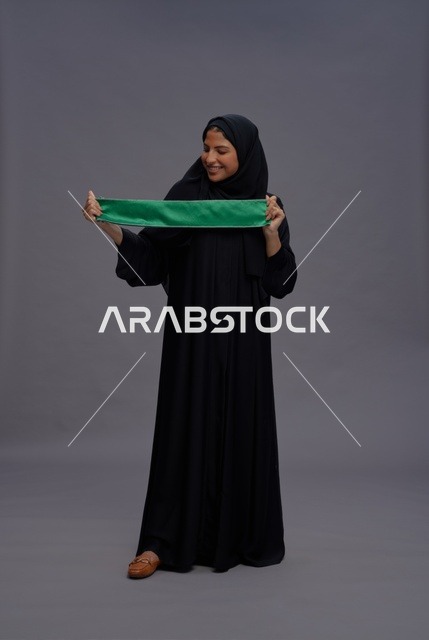 امرأة سعودية تحمل العلم الوطني في استوديو