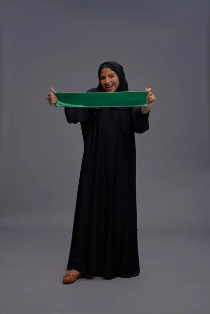 امرأة سعودية تحمل علم المملكة العربية السعودية باستوديو