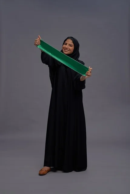 امرأة سعودية بالعباءة تحمل علم المملكة في الاستوديو