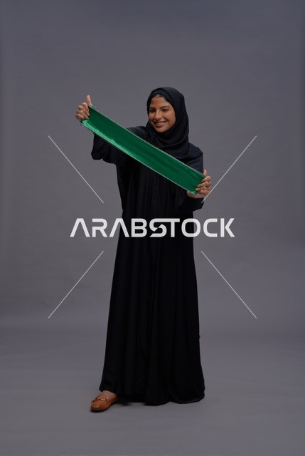 امرأة سعودية تحمل علم المملكة في الاستوديو