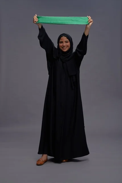 امرأة سعودية تمسك علم المملكة العربية السعودية في استوديو