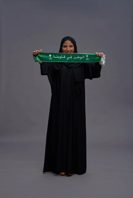Saudi Woman in Black Abaya Holding Green National Scarf