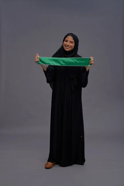 Saudi Woman Holding National Flag in Studio Portrait