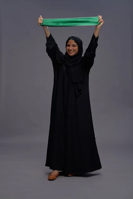 Saudi Woman Holding Kingdom Flag on Gray Background